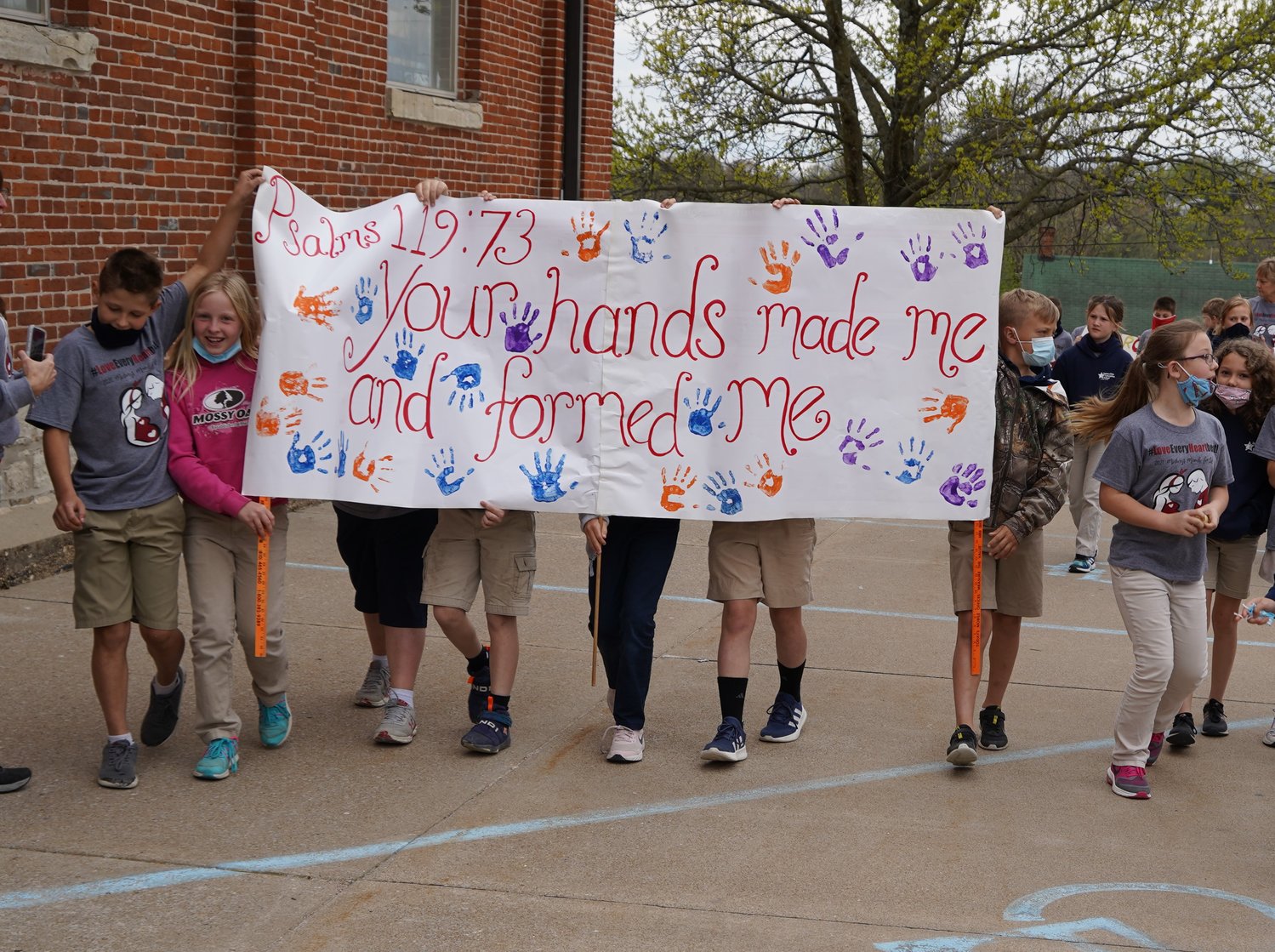 Students of Immaculate Conception School in Loose Creek carry signs and banners around the school and churchyard during a “mini march” for life on April 16.